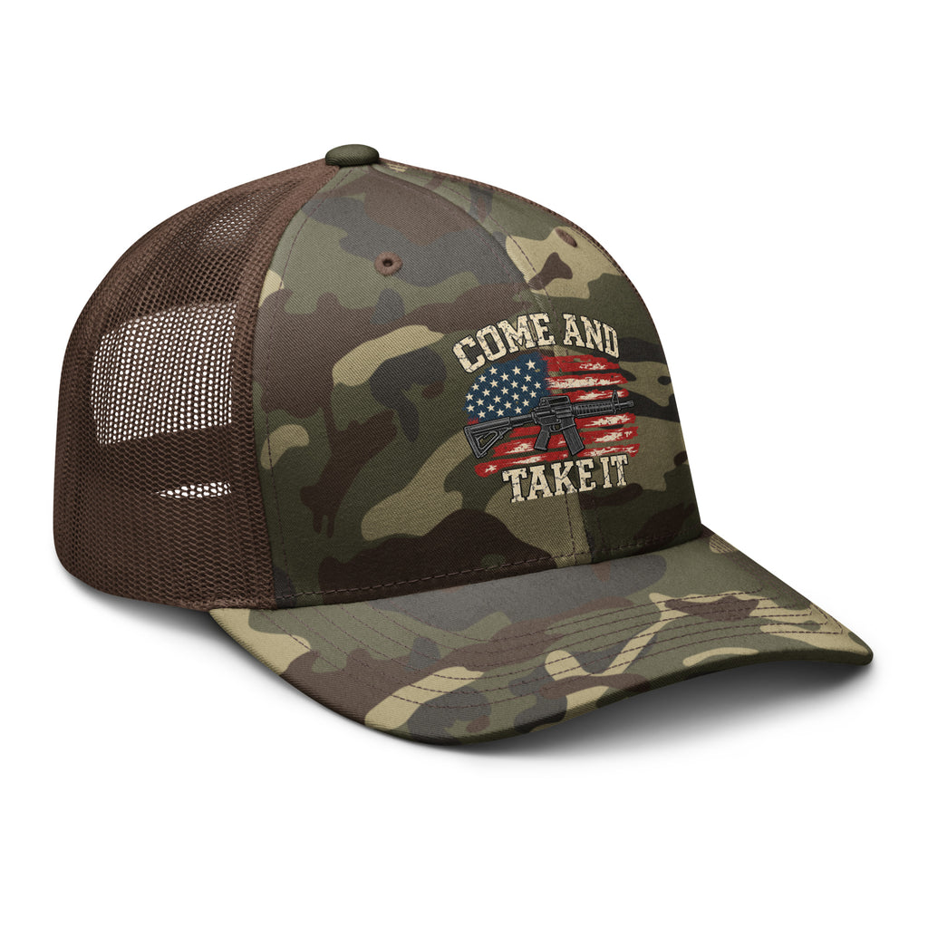 Angled front view of camouflage trucker hat with brown mesh back, Come and Take It lettering, American flag and rifle artwork