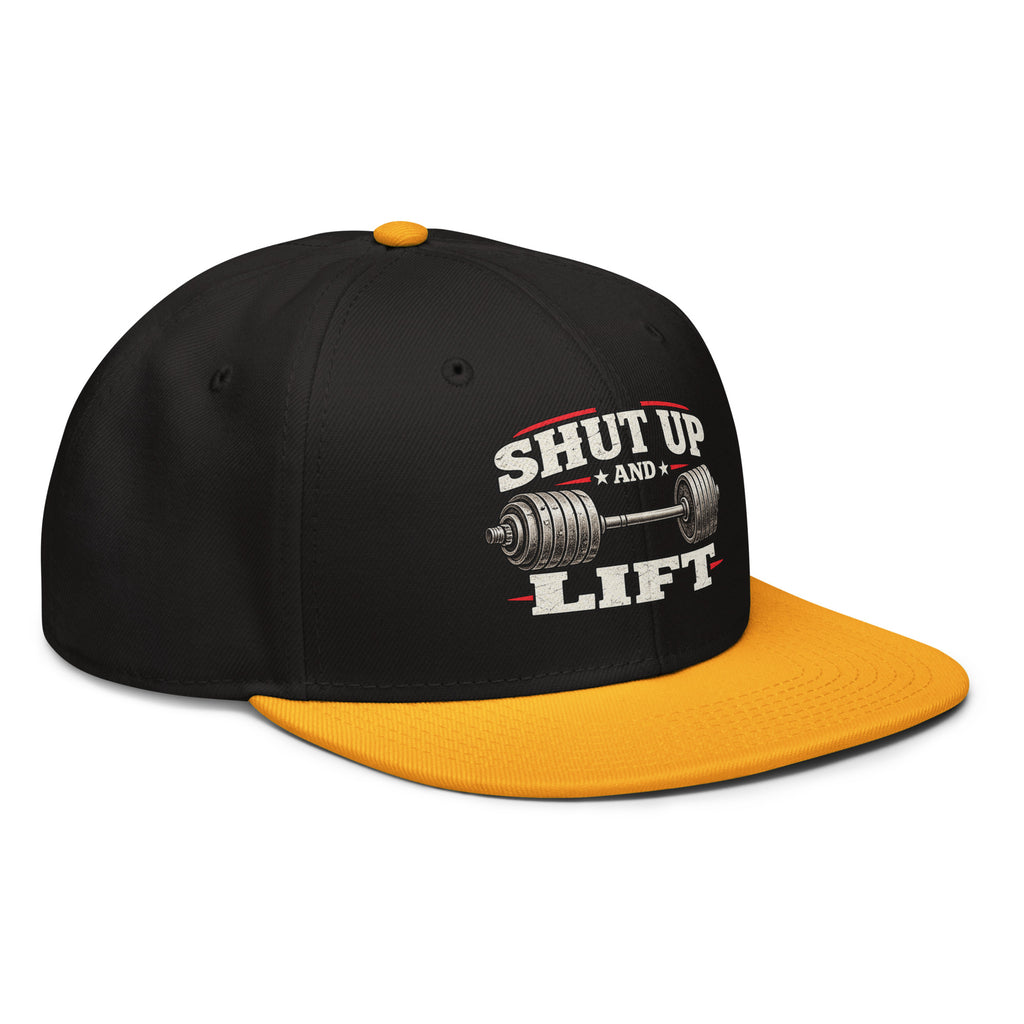 Angled front view of snapback hat, black with gold visor, featuring Shut Up and Lift lettering and a barbell graphic